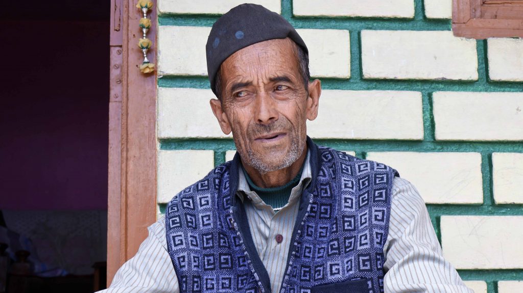 Chander Ram sitting in his courtyard, recounting his journey to Tibet, with the author seated beside him.