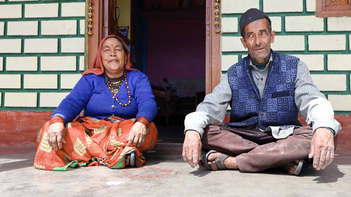 Chander Ram and his wife Haruli Devi standing in front of their stone and tin house in Sarmoli village, which they built after a landslide destroyed their home in Sai village.