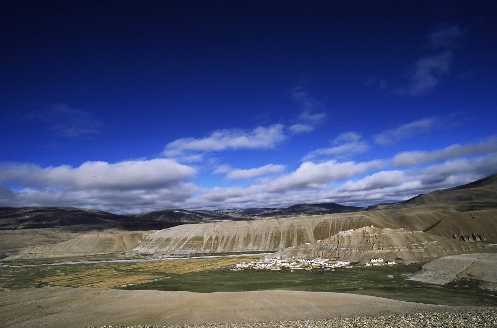 Barren, expansive high-altitude landscape in Tibet, with rocky terrain and distant mountains.